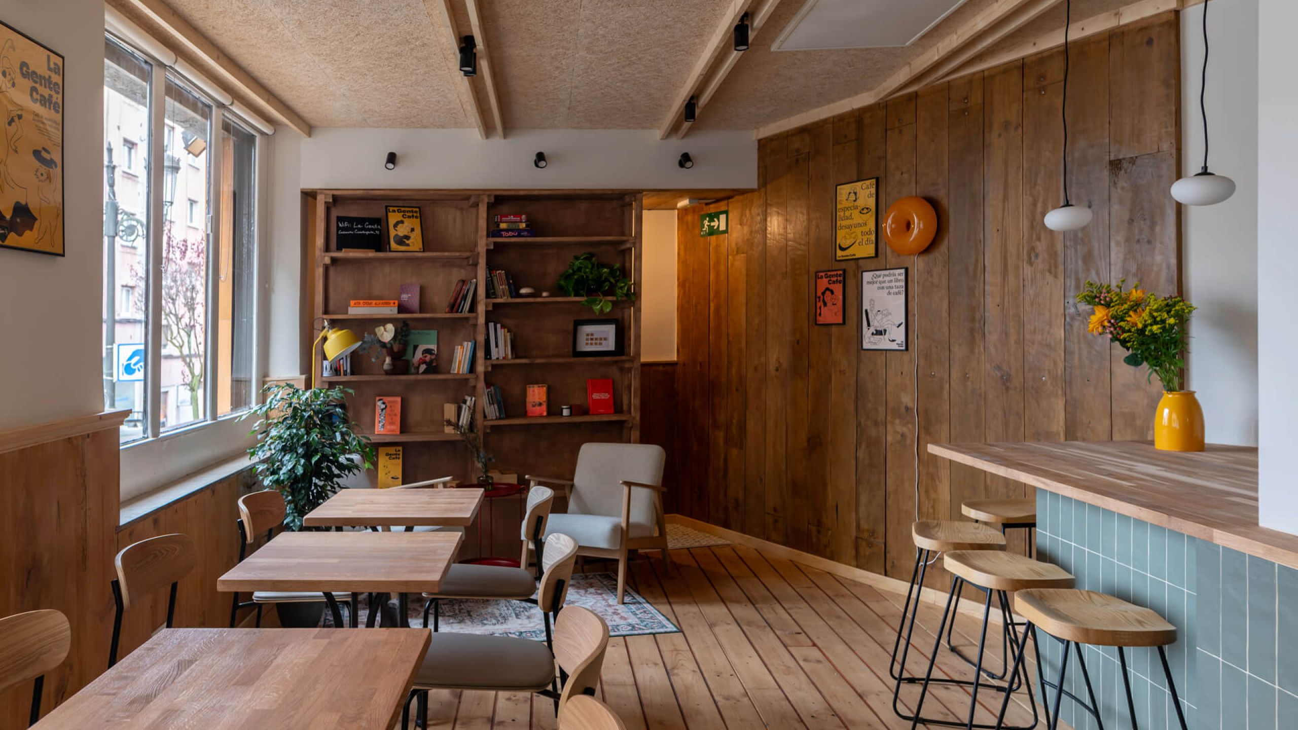 A cozy La Gente Cafe interior featuring wooden walls and floors, designed by TenZeroTwo Bureau