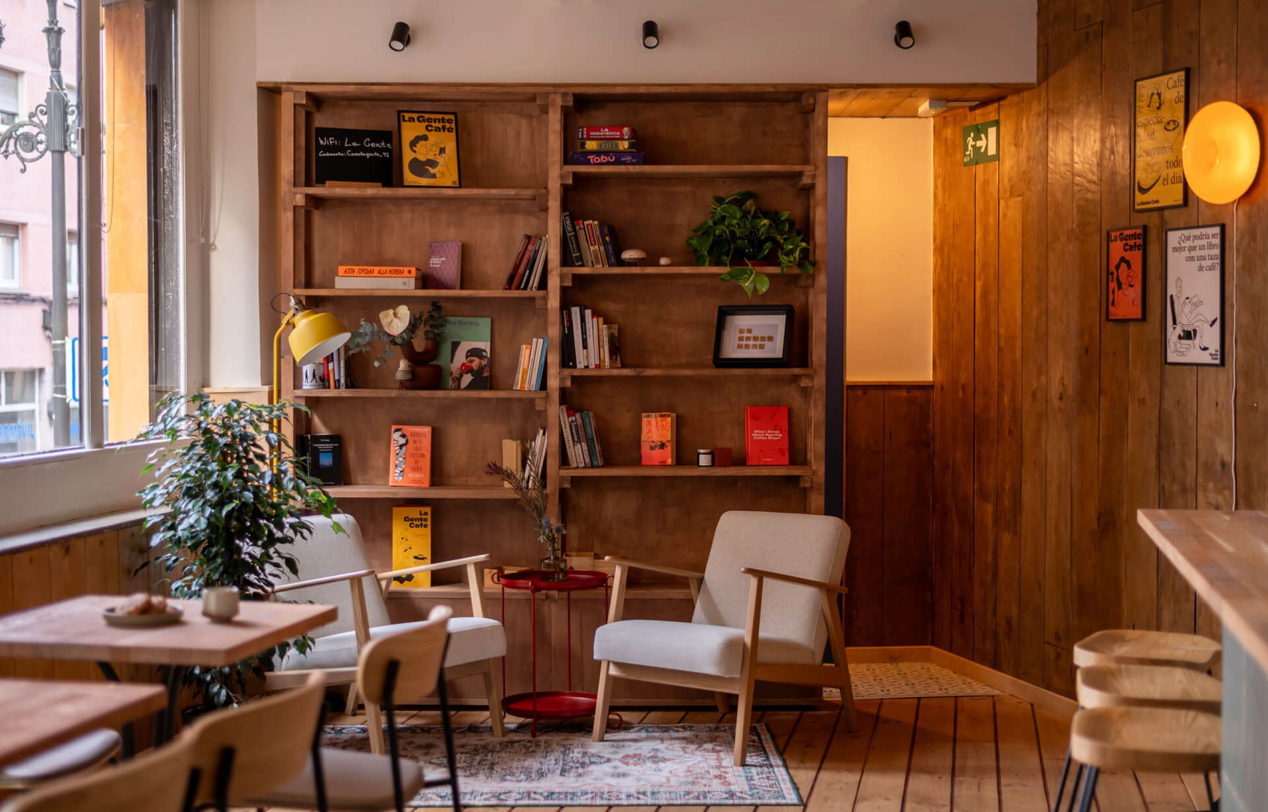A cozy La Gente Cafe with wooden floors and a bookshelf, designed by TenZeroTwo Bureau