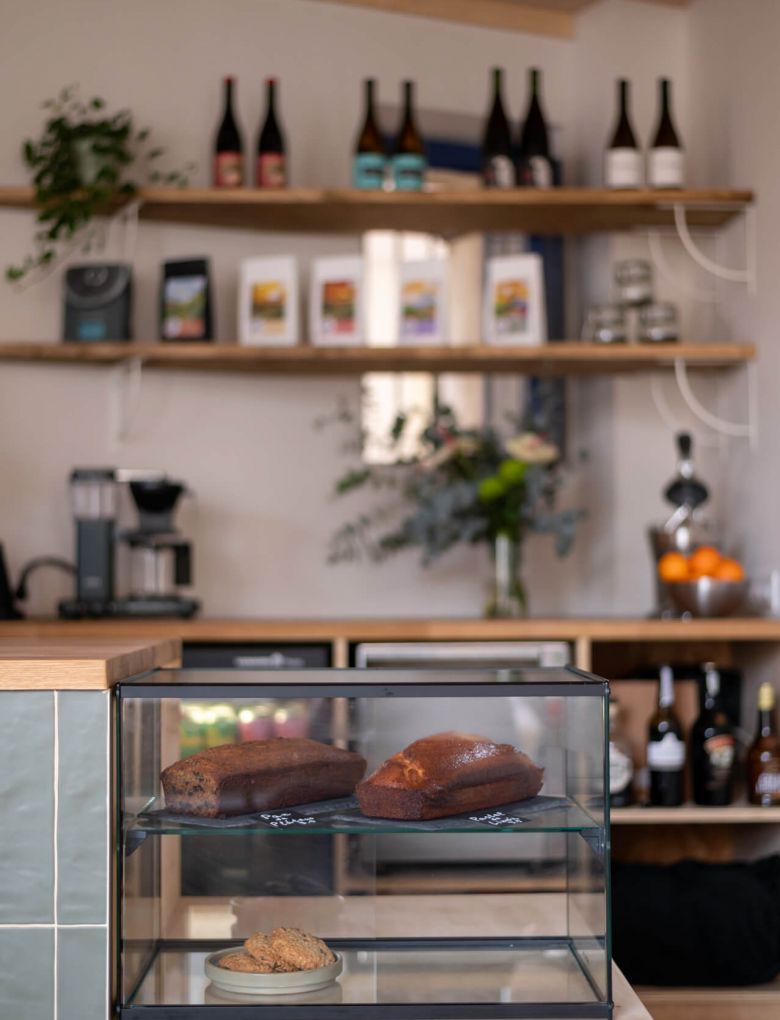 Counter at La Gente Cafe featuring a display case filled with various food items, designed by TenZeroTwo Bureau