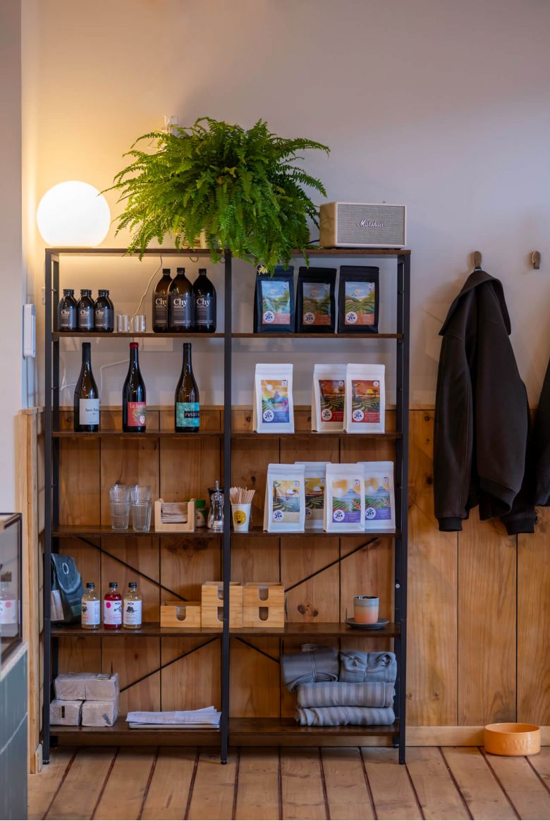 A shelf at La Gente Cafe displays various bottles and vibrant plants, designed by TenZeroTwo Bureau