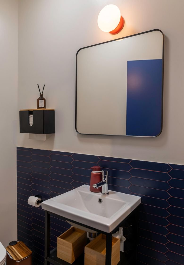 A stylish bathroom at La Gente Cafe featuring a sink, toilet, and mirror, designed by TenZeroTwo Bureau