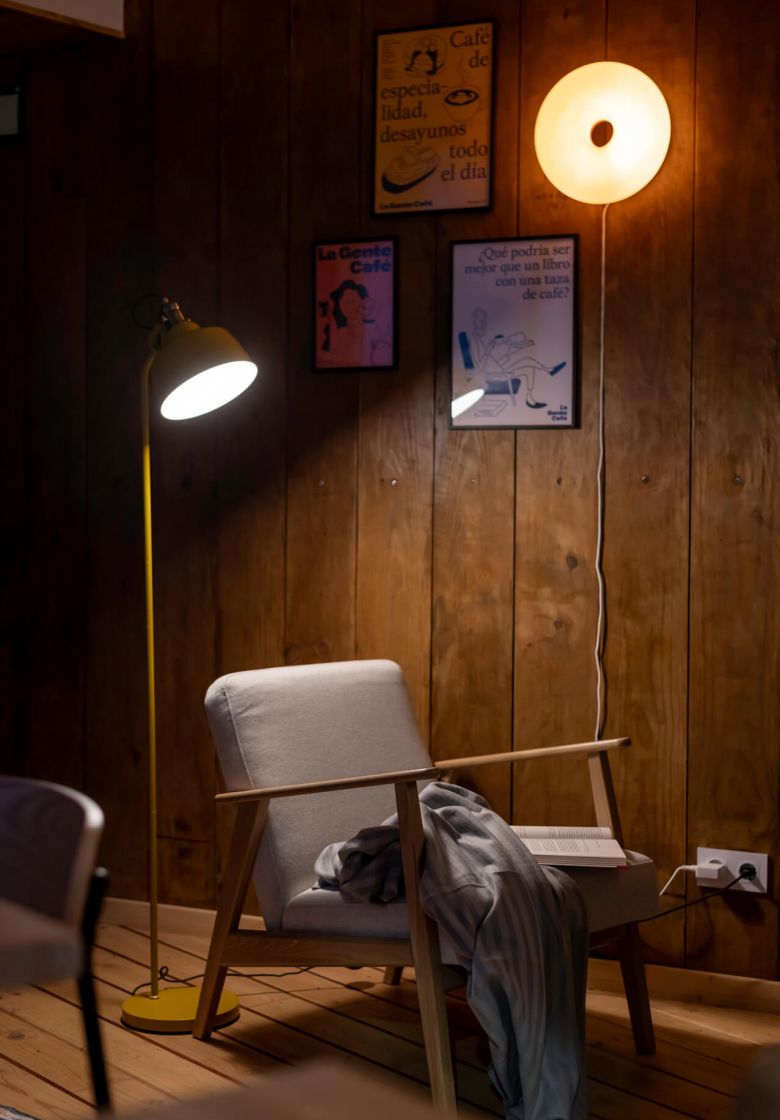 A cozy chair and lamp in La Gente Cafe, featuring warm wooden walls, designed by TenZeroTwo Bureau